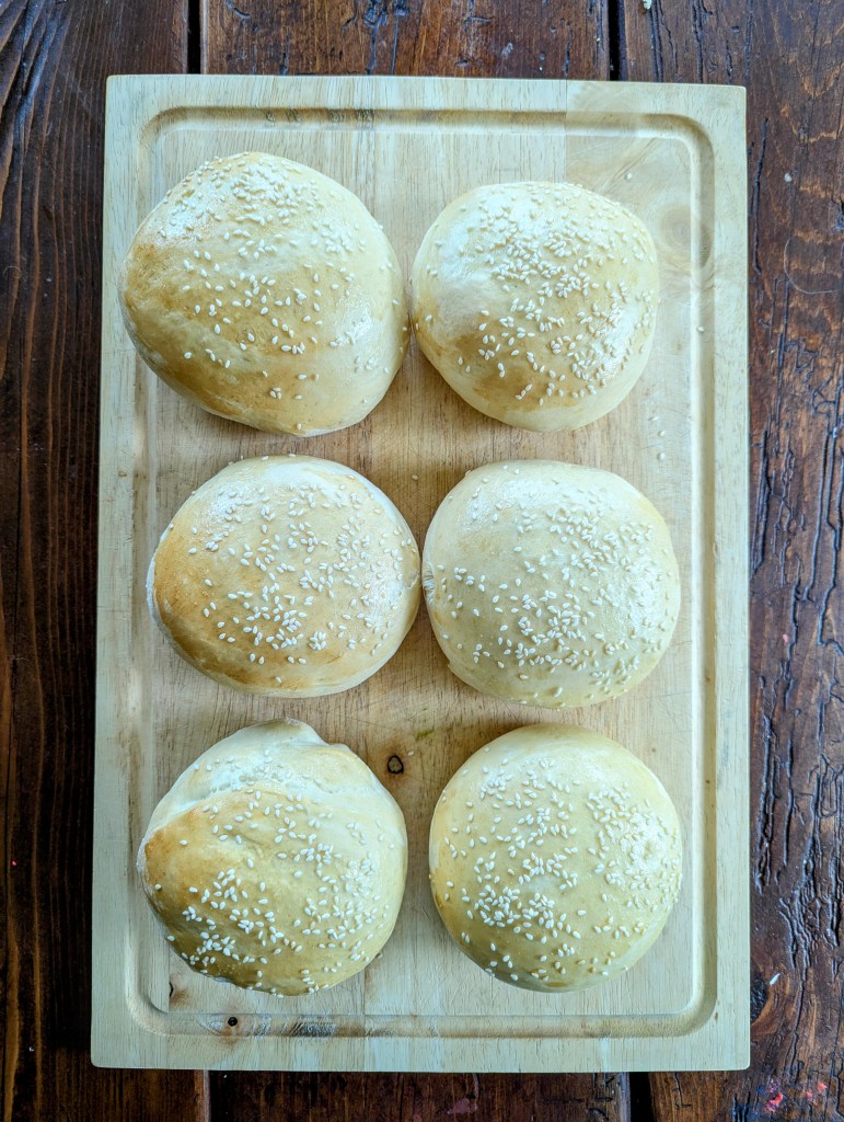 Homemade sourdough discard hamburger buns on wooden cutting board