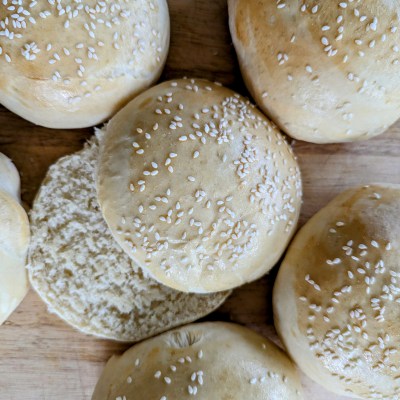 Golden sourdough hamburger buns on wooden tablle