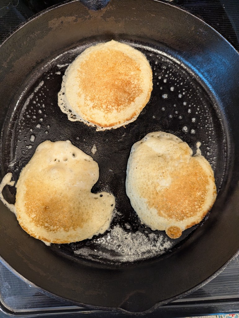 high protein sourdough discard pancakes in a cast iron skillet