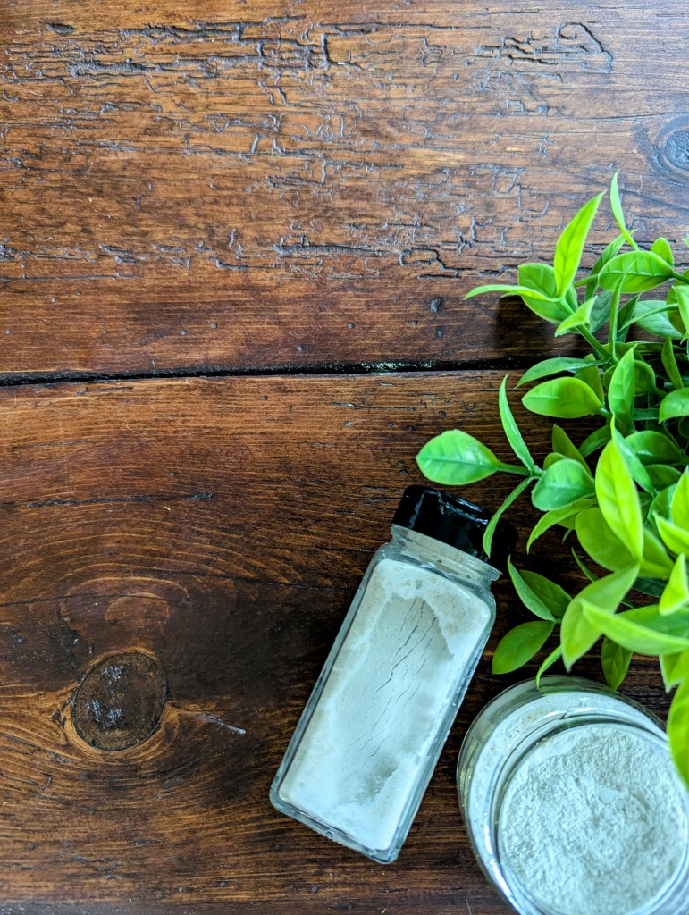DIY talc-free baby powder in a glass jar on a wooden farmhouse table