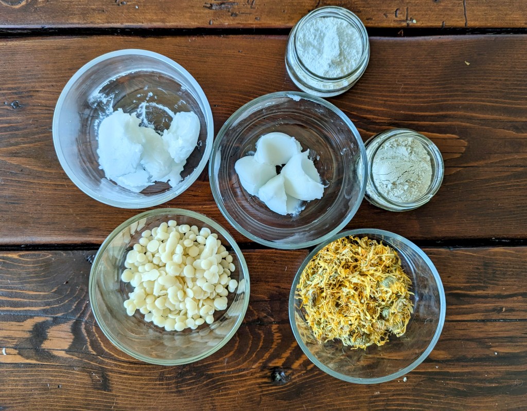 Ingredients for DIY diaper rash ointment cream including coconut oil and dried calendula flowers