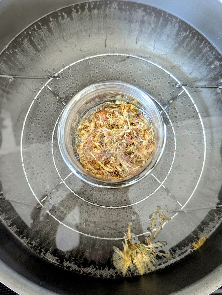 Infusing coconut oil with dried calendula flwers on the stovetop