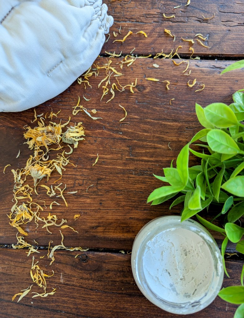 Homemade diaper rash cream with calendula flowers on a wooden farmhouse table