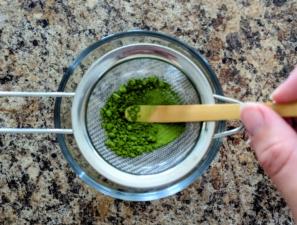 Sifting ceremonial grade matcha powder for an iced lavender matcha latte