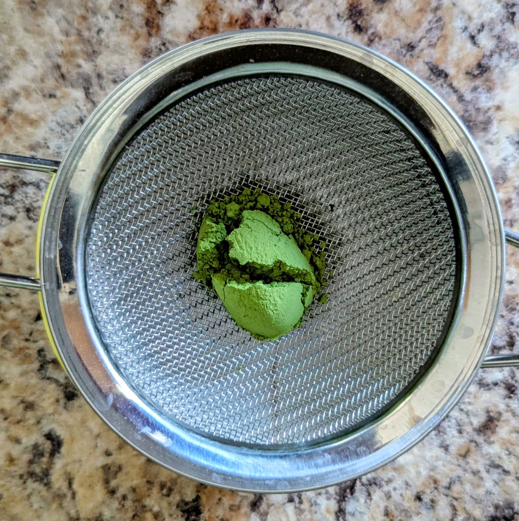Sifting matcha powder for a strawberry matcha latte