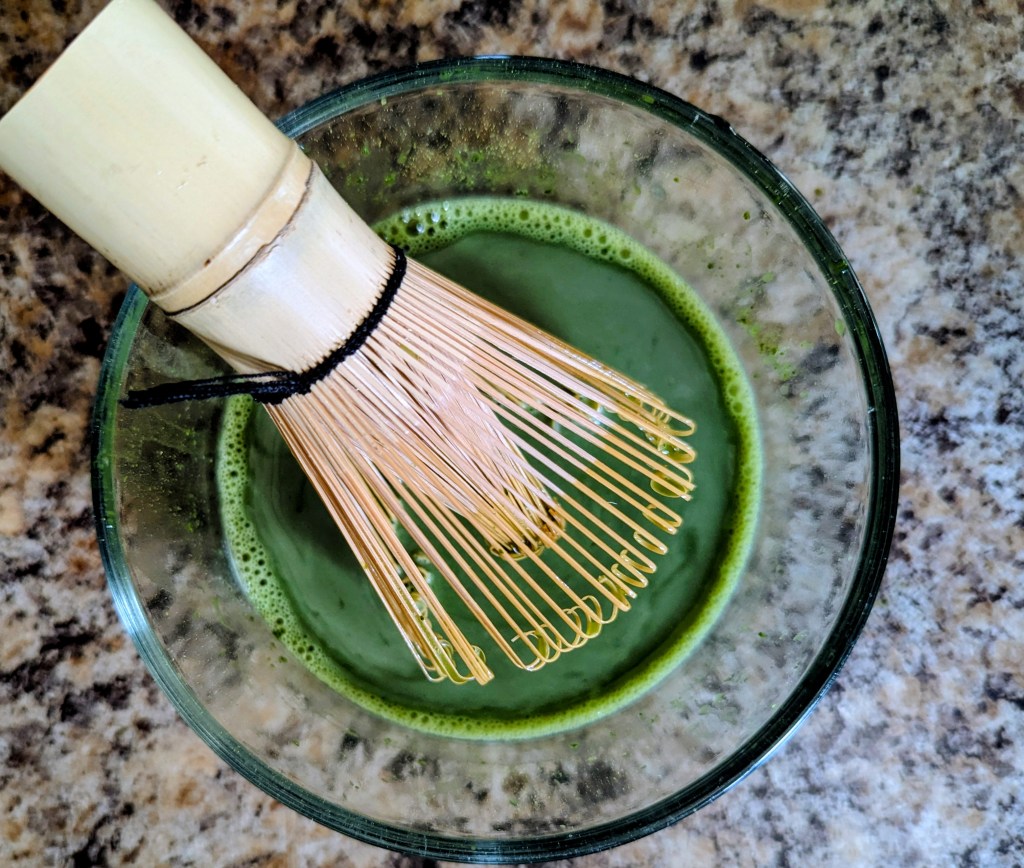Whisking matcha powder with a bamboo whisk for a strawberry matcha latte