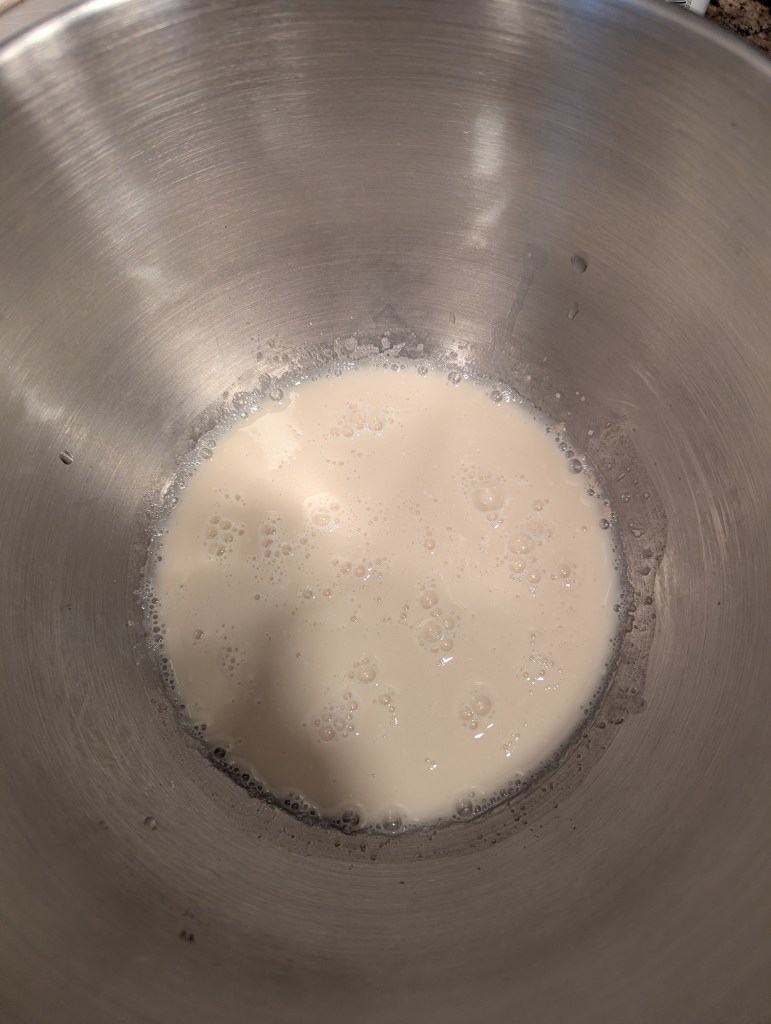 Sourdough discard, water, and yeast in a steel bowl