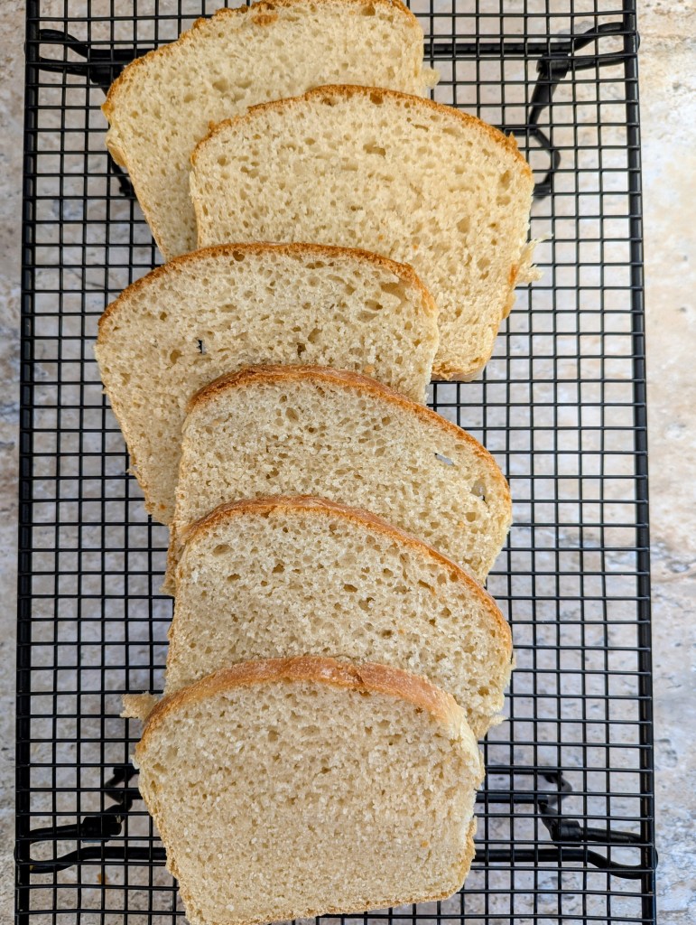 Sliced sourdough sandwich bread on a cooling rack