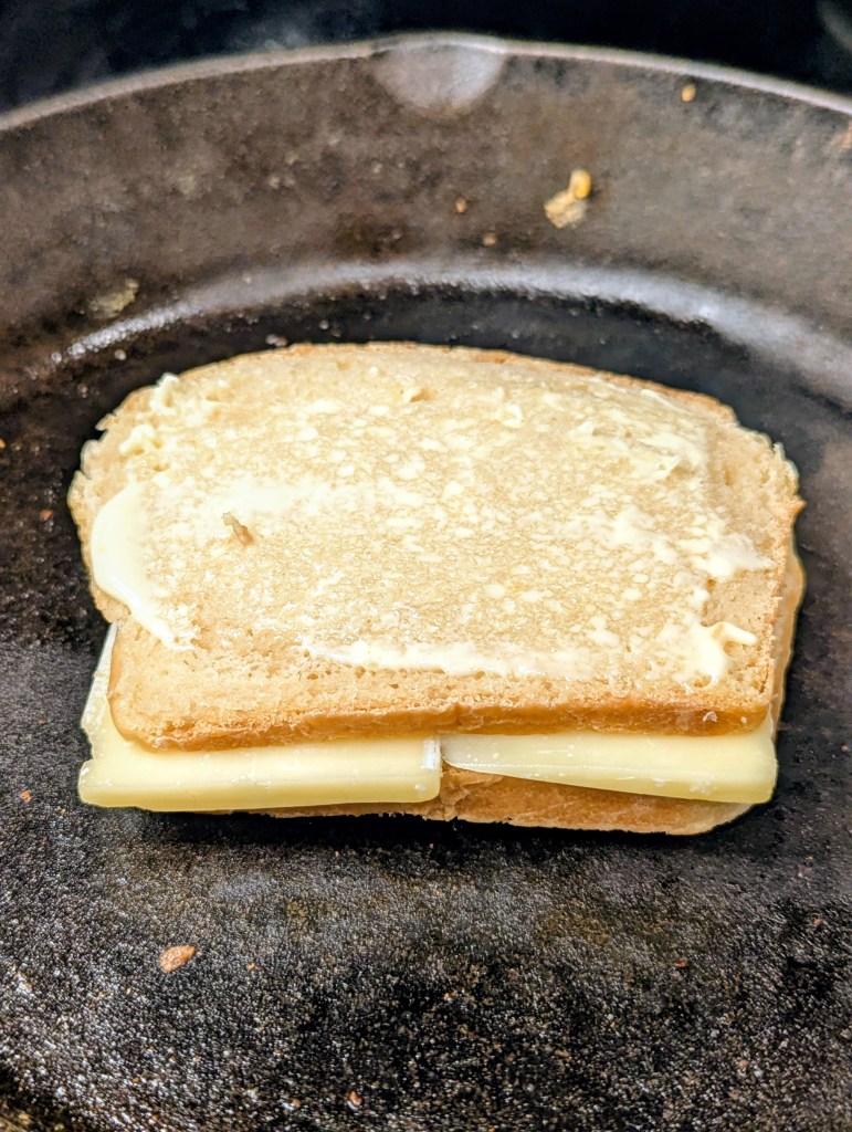 Side angle of sourdough grilled cheese cooking in a skillet
