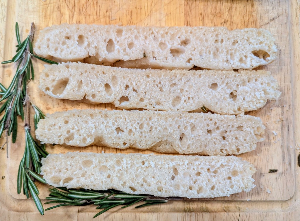 Sliced sourdough focaccia on a wooden cutting board