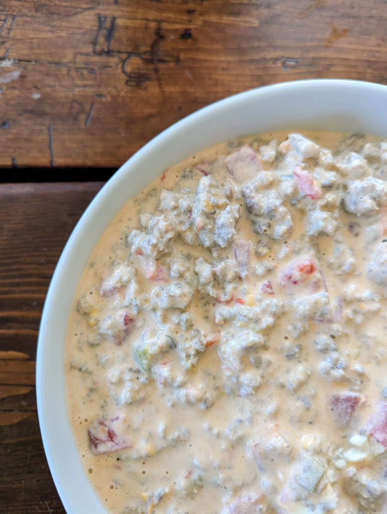 Aerial shot of dip with sausage rotel and cream cheese on a farmhouse table