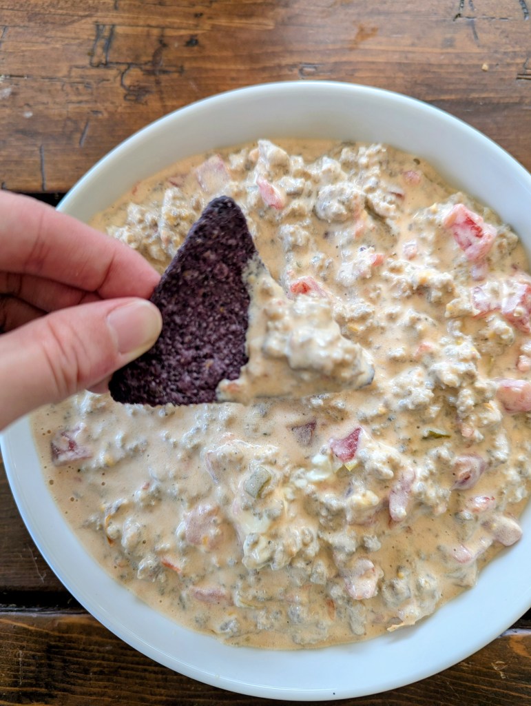 Dipping a chip into dip with sausage, rotel, and cream cheese