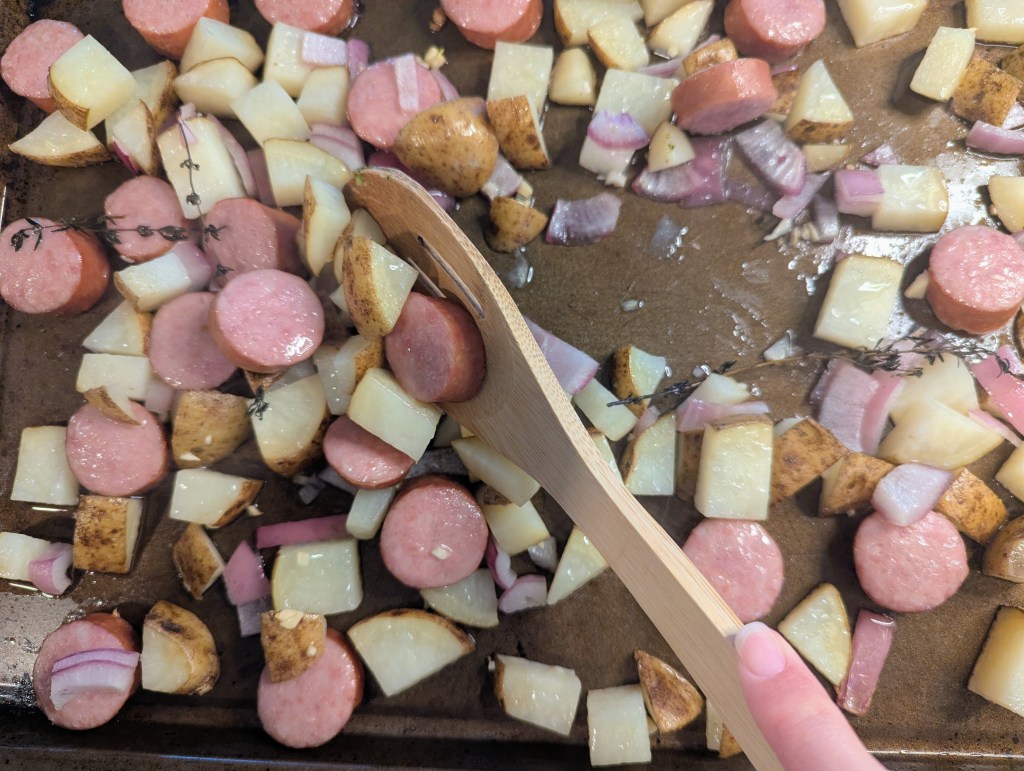 Stirring kielbasa and potatoes while roasting