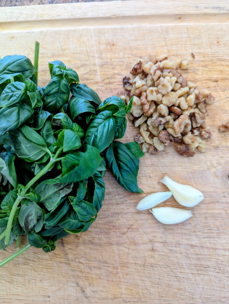 Ingredients for pesto recipe with walnuts on a wooden cutting board