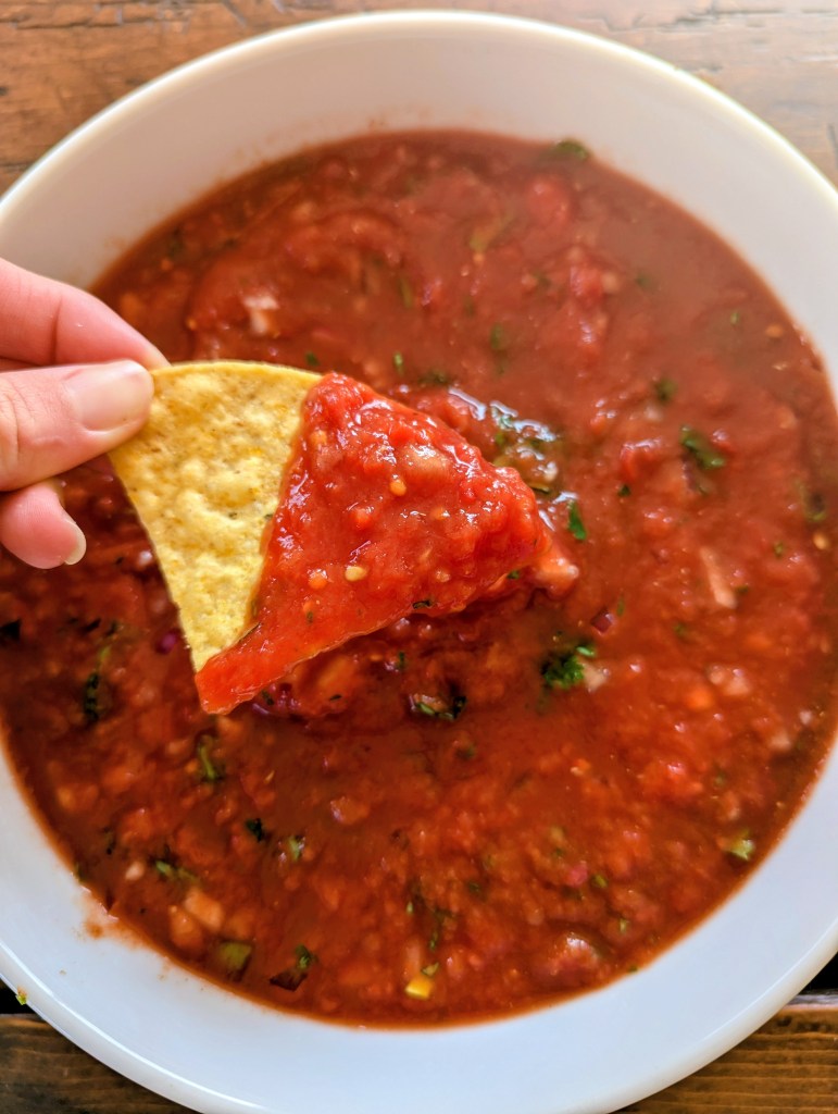 Dipping a chip into homemade salsa with canned tomatoes