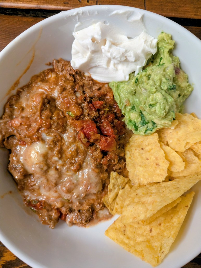 Taco casserole recipe topped with sour cream and guacamole