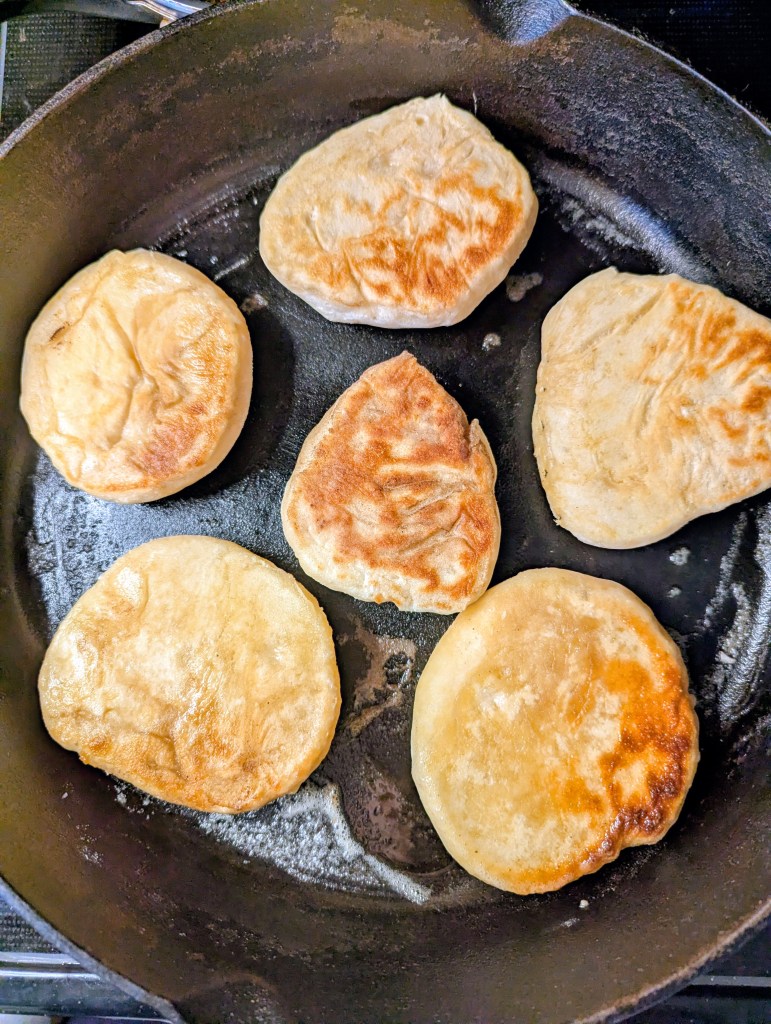 Cooking sourdough English muffin recipe in cast-iron skillet