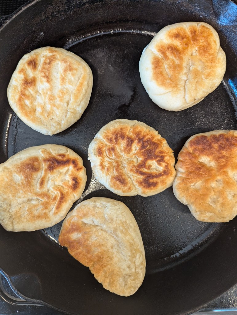 cooking sourdough discard English muffins in a cast-iron skillet