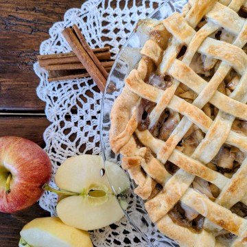 Aerial shot of sourdough apple pie with sliced apples and cinnamon sticks